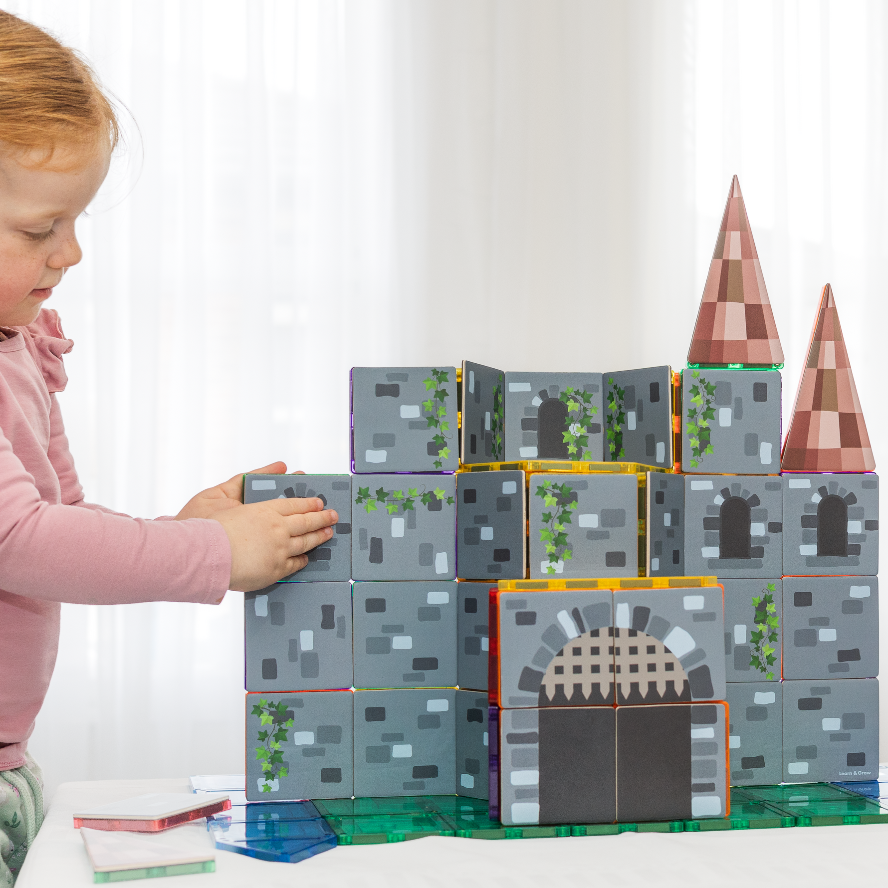 Girl playing with a castle made from magnetic tile toppers