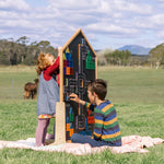 Children playing on either side of the learn & grow toys mutli-board sitting outside on a farm 