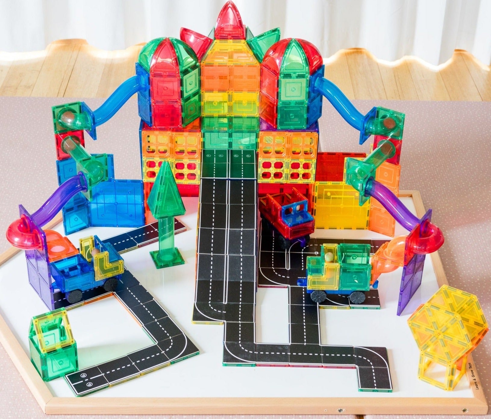 A mega city made from magnetic tiles and toppers from Learn and Grow Toys sitting on a Multi-Board used as a base plate