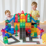 Two children playing with mega city made from magnetic tiles and toppers from Learn and Grow Toys sitting on a Multi-Board used as a base plate