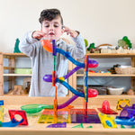 Child playing with marble ball run set up using magnetic tiles from Learn & Grow Toys