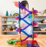 Child peering through magnetic marble ball run set on wooden table 