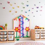 Multi-Board set up on wall with rainbow coloured ball run and poppies made of magnetic tiles with colourful butterflies on wall in a playroom