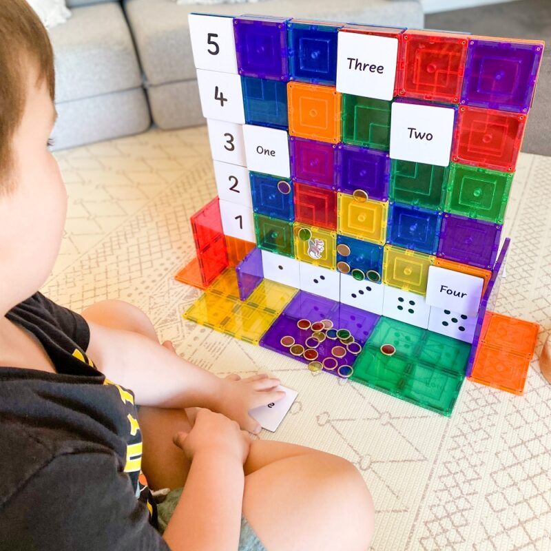 Child playing with numeracy tile toppers set up on rainbow magnetic tile small squares