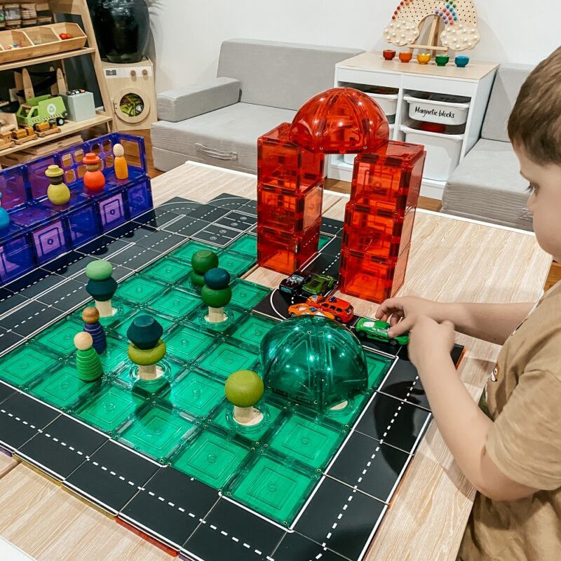 Child playing with road toppers and dome pack on table