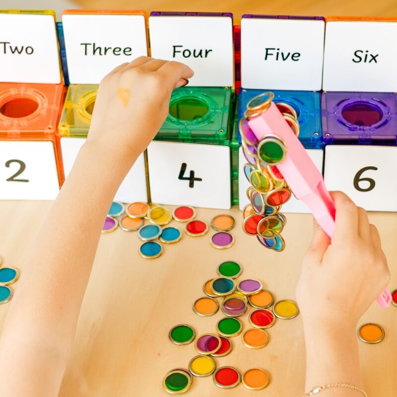 Child using learn and grow toys magnetic wand with metal rimmed counting chips and tiles andChild using learn and grow toys magnetic wand with metal rimmed counting chips and tiles and numeracy toppers numeracy toppers