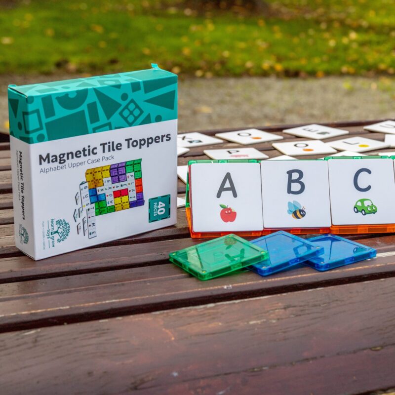 Learn and Grow tile toppers in uppercase alphabet sitting outside with packaging and with ABC