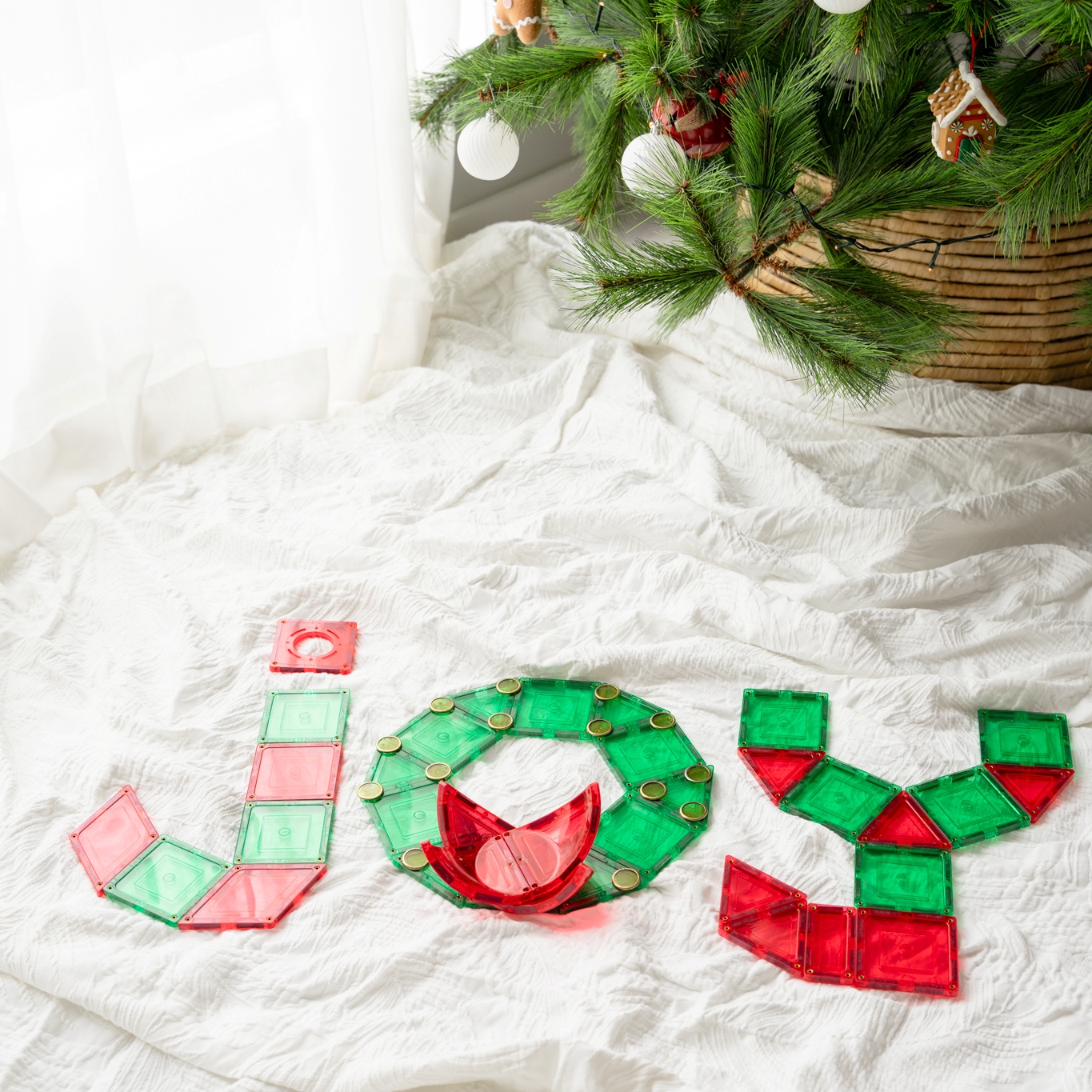 Joy spelt in learn and grow toys magnetic tiles with christmas tree in background
